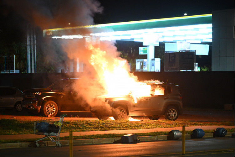 Veículo incendiado diante de posto de gasolina durante atos de violência e vandalismo cometidos por apoiadores do presidente Jair Bolsonaro, em Brasília