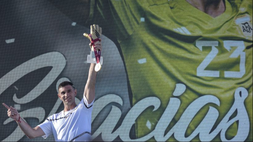 O goleiro da seleção argentina Emiliano Martinez segura medalha de ouro e troféu luva de ouro concedidos pela FIFA durante homenagem a ele, em Mar del Plata, Argentina, em 22 de dezembro de 2022, ao retornar à sua cidade natal após vencer o Catar 2022 torneio da Copa do Mundo 