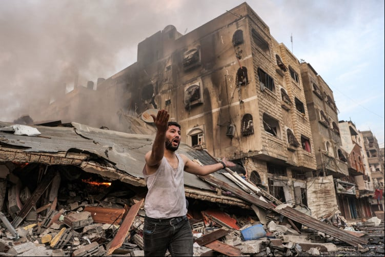 Homem reage do lado de fora de um prédio desabado em chamas após bombardeio israelense na cidade de Gaza em 11 de outubro de 2023