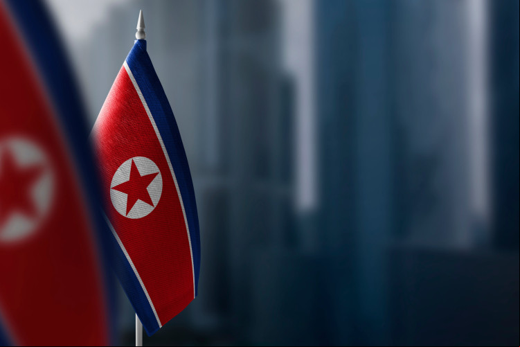 Pequenas bandeiras da Coreia do Norte sobre um fundo desfocado da cidade Pequenas bandeiras da Coreia do Norte sobre um fundo desfocado da cidade