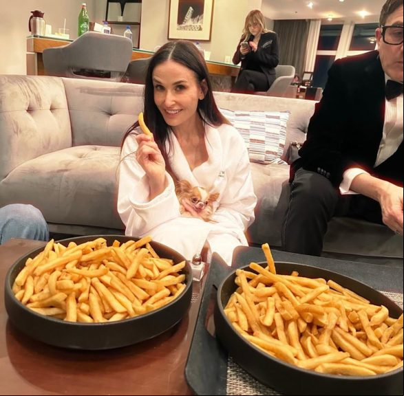 Em uma foto postada por sua filha, Moore aparece sentada no chão de roupão, com seu cachorro no colo e com duas tigelas cheias de batata frita ao lado.