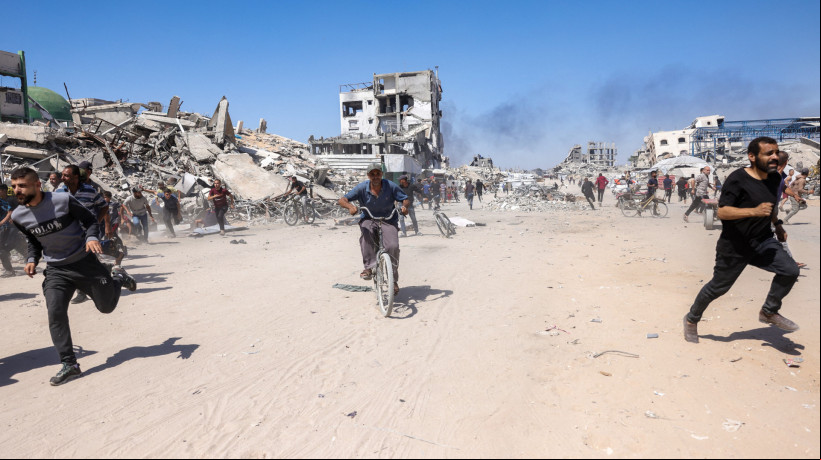 Palestinos correm para se proteger do ataque de drone israelense em Jabalia, no norte da Faixa de Gaza, em 23 de maio de 2025